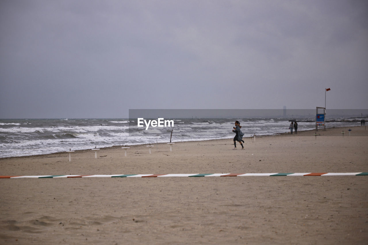 PEOPLE AT BEACH AGAINST SKY