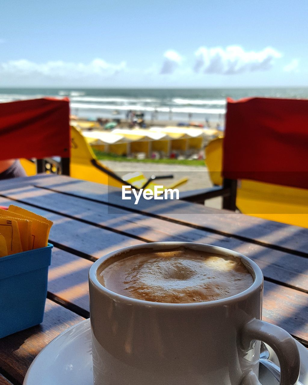 CLOSE-UP OF COFFEE CUP ON TABLE BY SEA