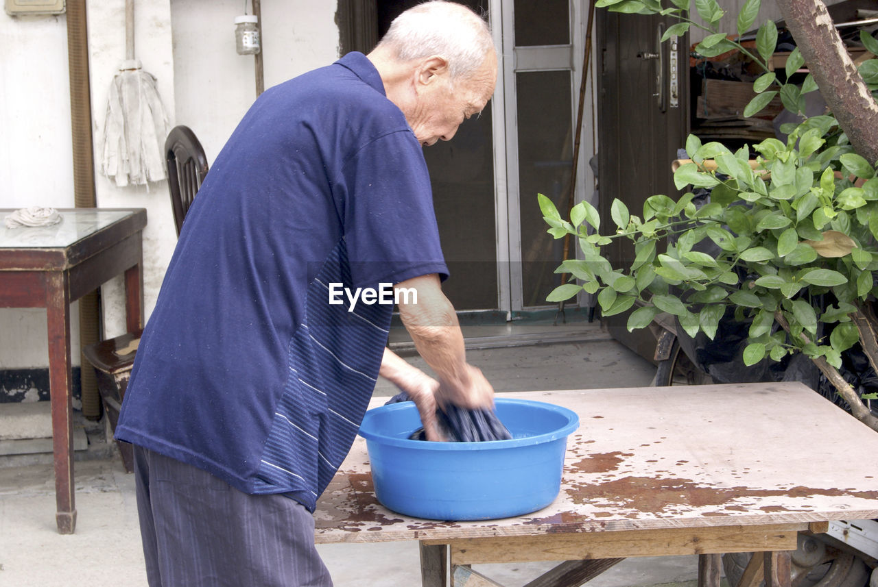 SIDE VIEW OF MAN HOLDING UMBRELLA WHILE STANDING AT YARD