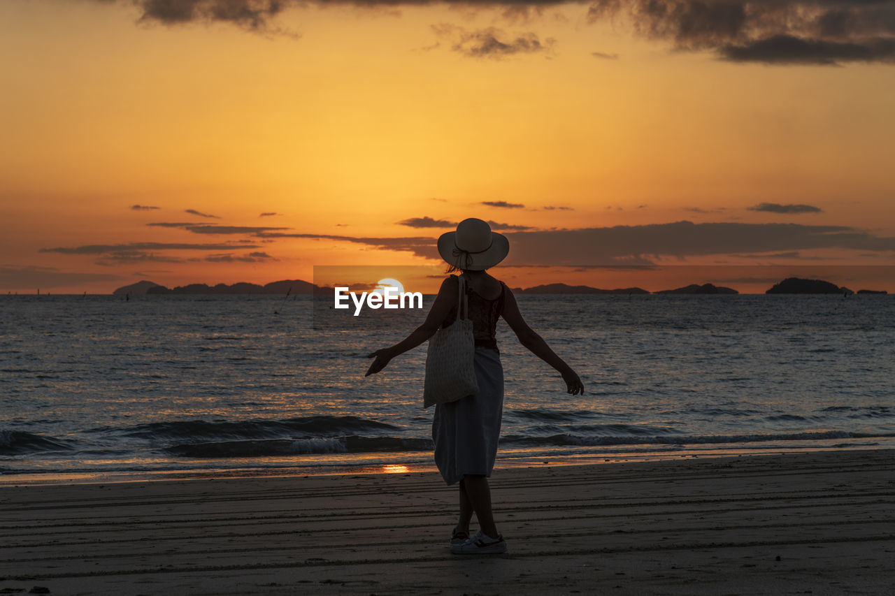 Full length of woman standing on beach during sunset