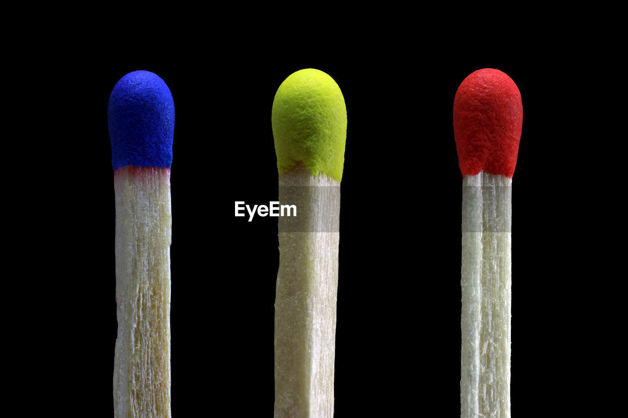 Close-up of multi colored matchsticks against black background