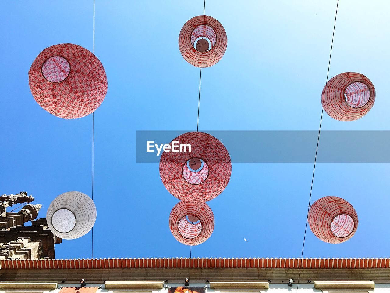 Low angle view of lanterns against clear blue sky