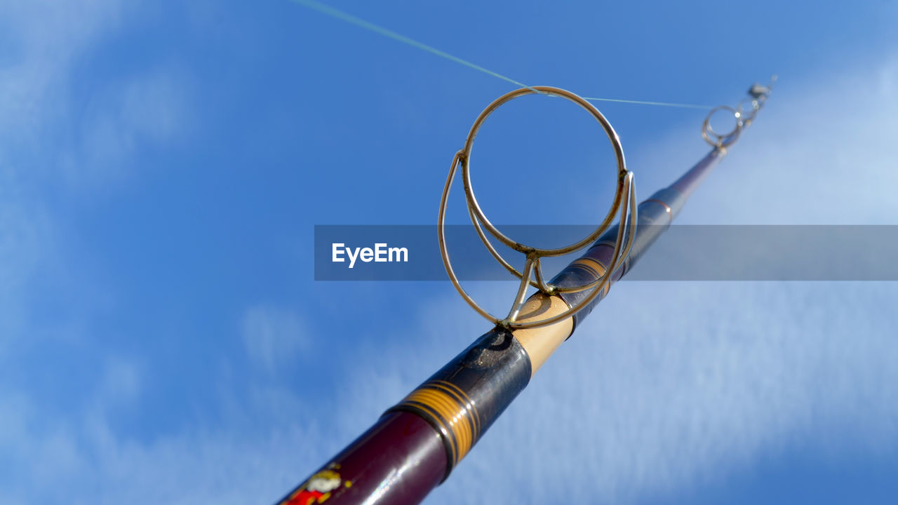 Close-up low angle view of fishing rod against blue sky