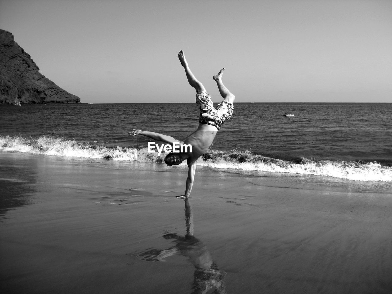 Man doing handstand at beach against sky