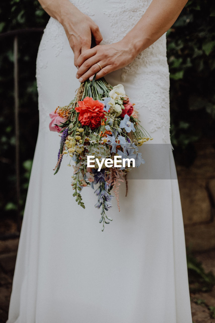 Midsection of bride holding bouquet