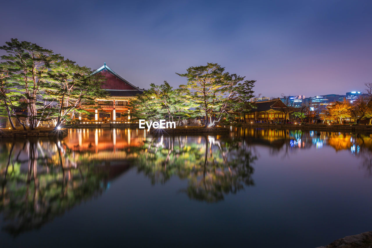 reflection of building in lake against sky at night