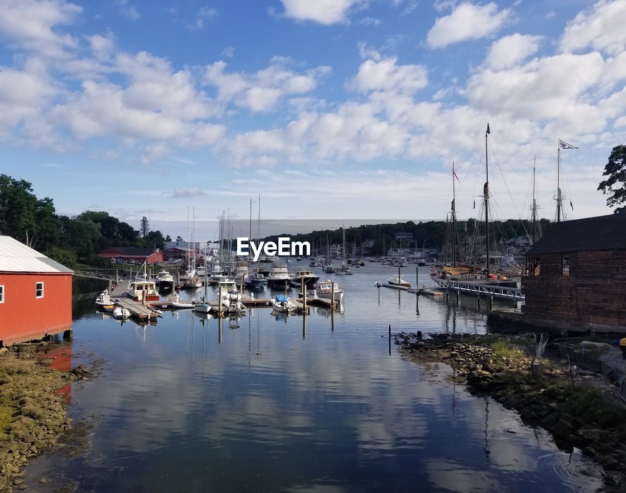 Boats moored at harbor in city against sky