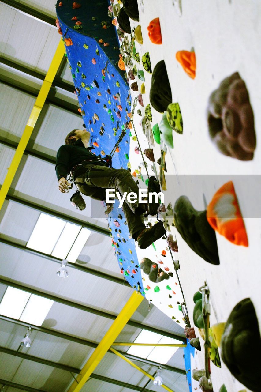 Low angle view of man climbing artificial wall
