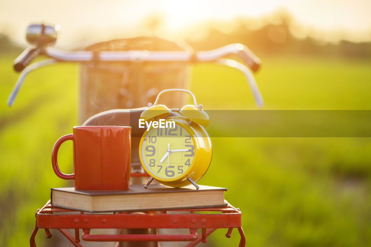 CLOSE-UP OF CLOCK ON TABLE AGAINST FIELD