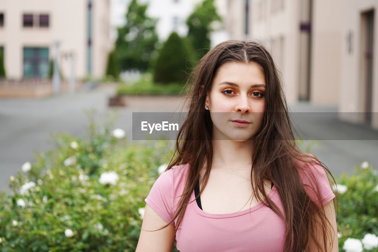 Portrait of beautiful young woman standing against plants