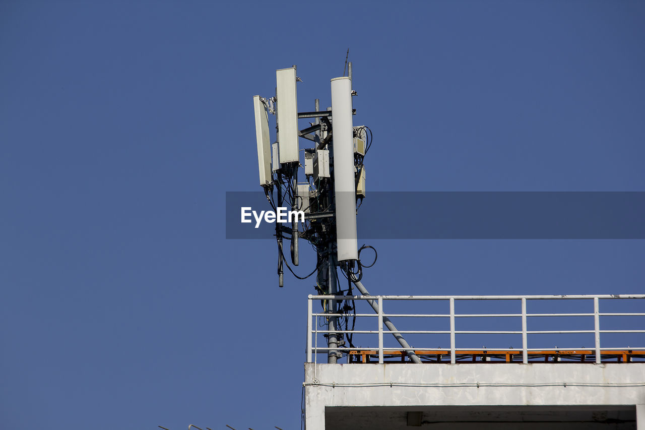 Low angle view of communications tower against clear blue sky