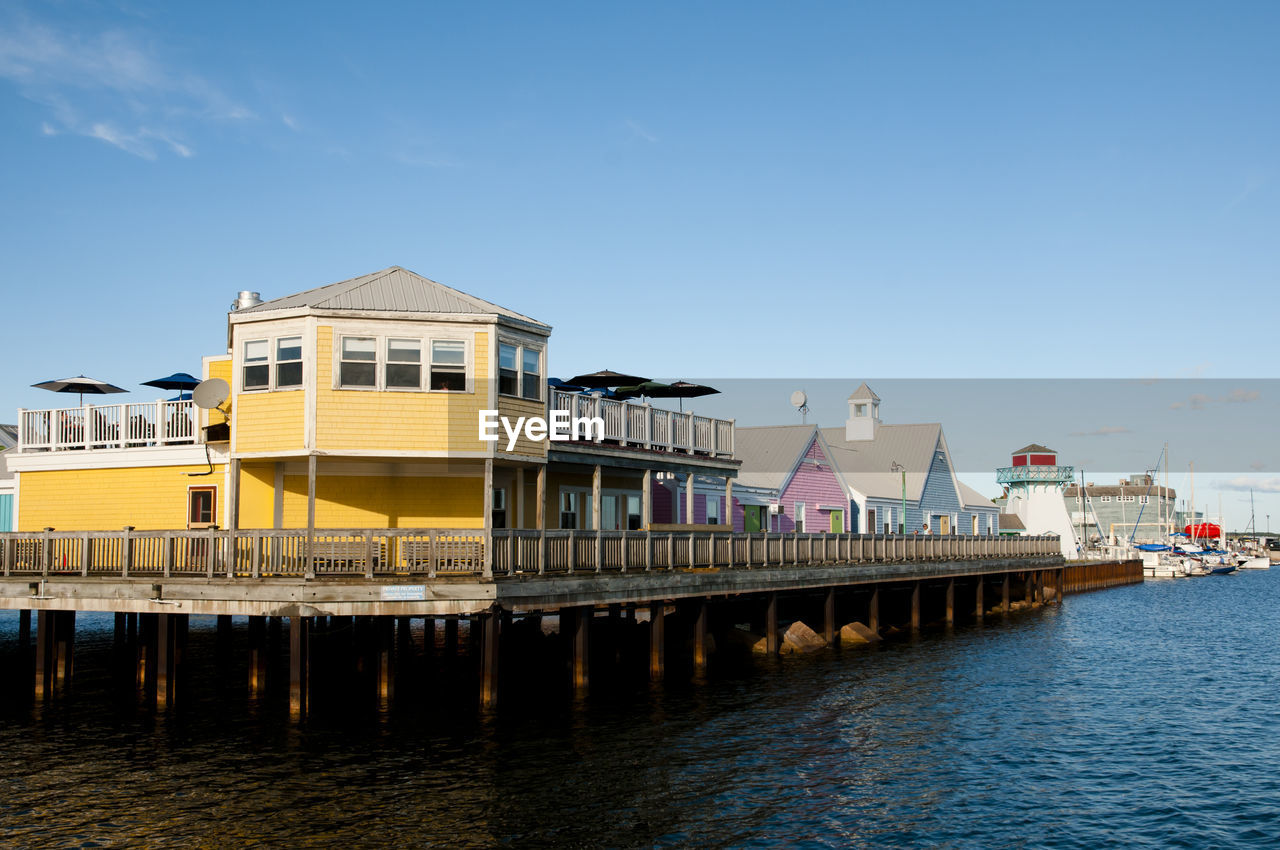 Buildings by river against blue sky