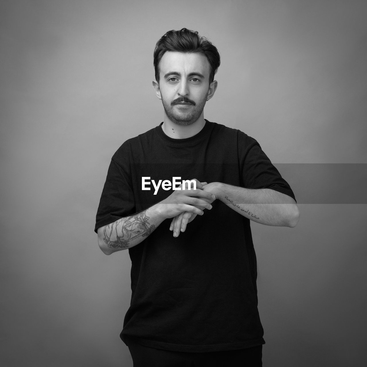 PORTRAIT OF YOUNG MAN AGAINST GRAY BACKGROUND