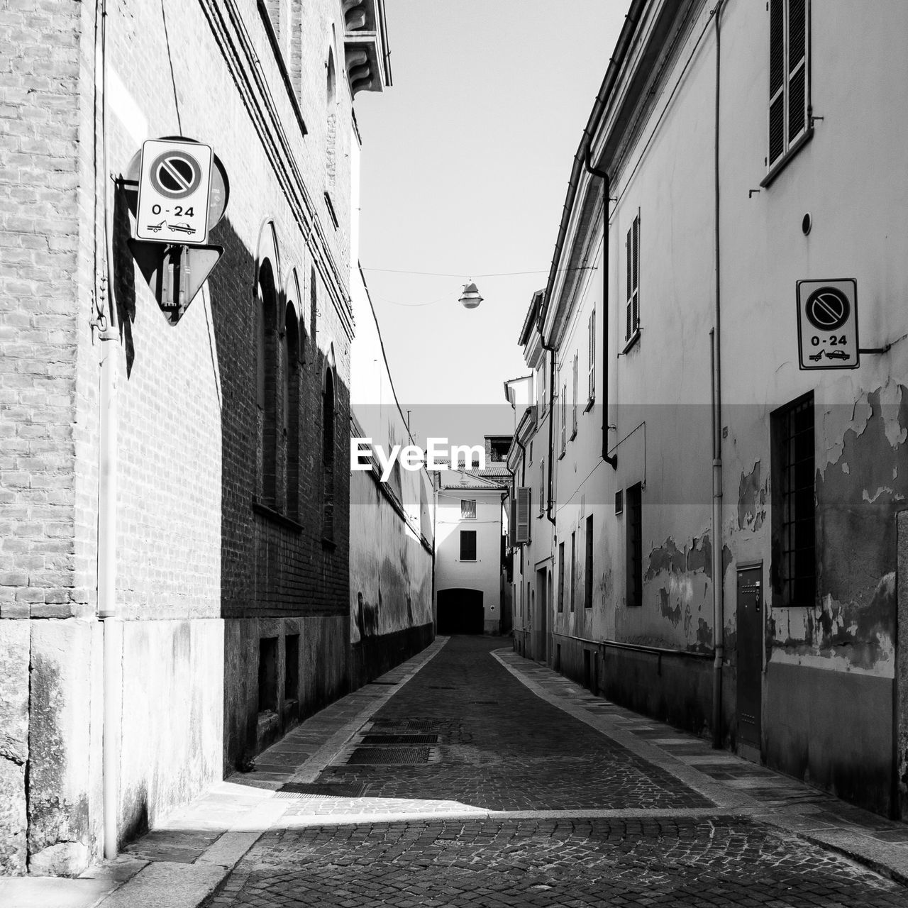 NARROW STREET AMIDST BUILDINGS AGAINST SKY