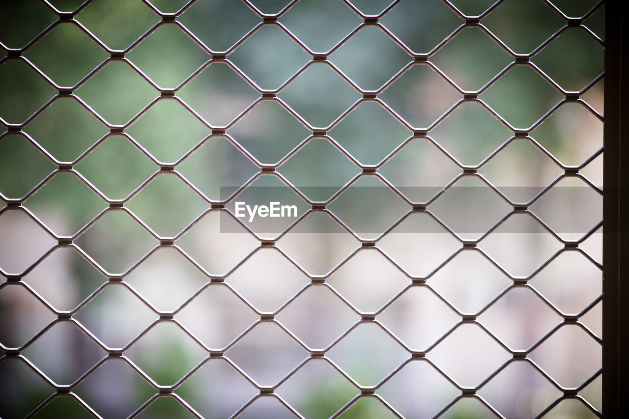 CLOSE-UP OF CHAINLINK FENCE AGAINST BLURRED SKY