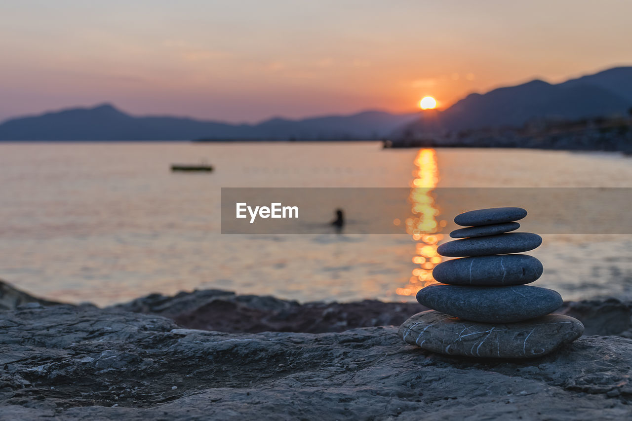 Stack of stones against sea and sky during sunset