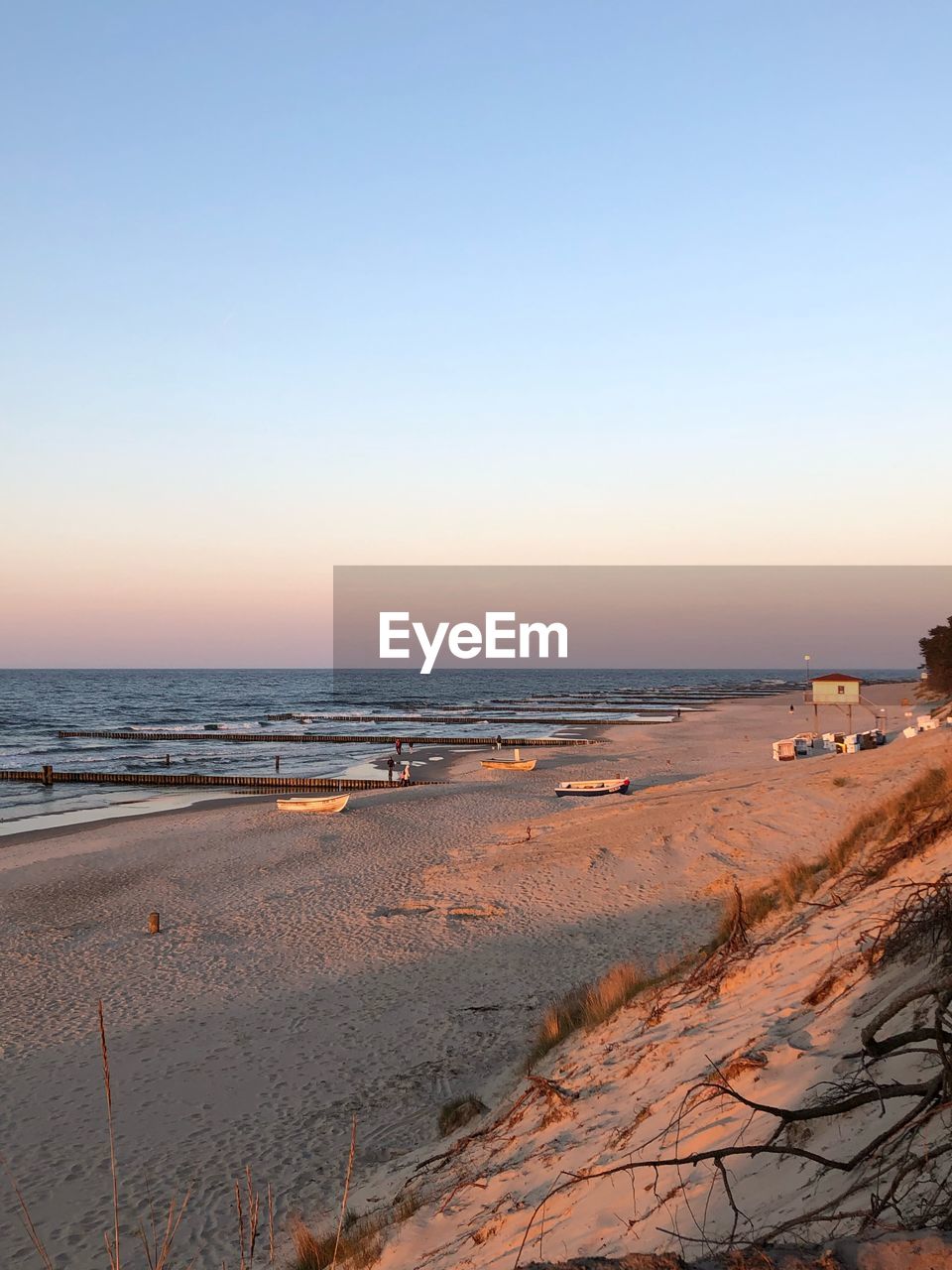 Scenic view of beach against clear sky during sunset