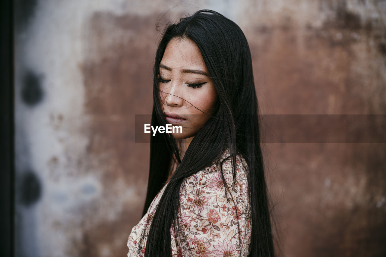 Beautiful woman with eyes closed by rusty iron door