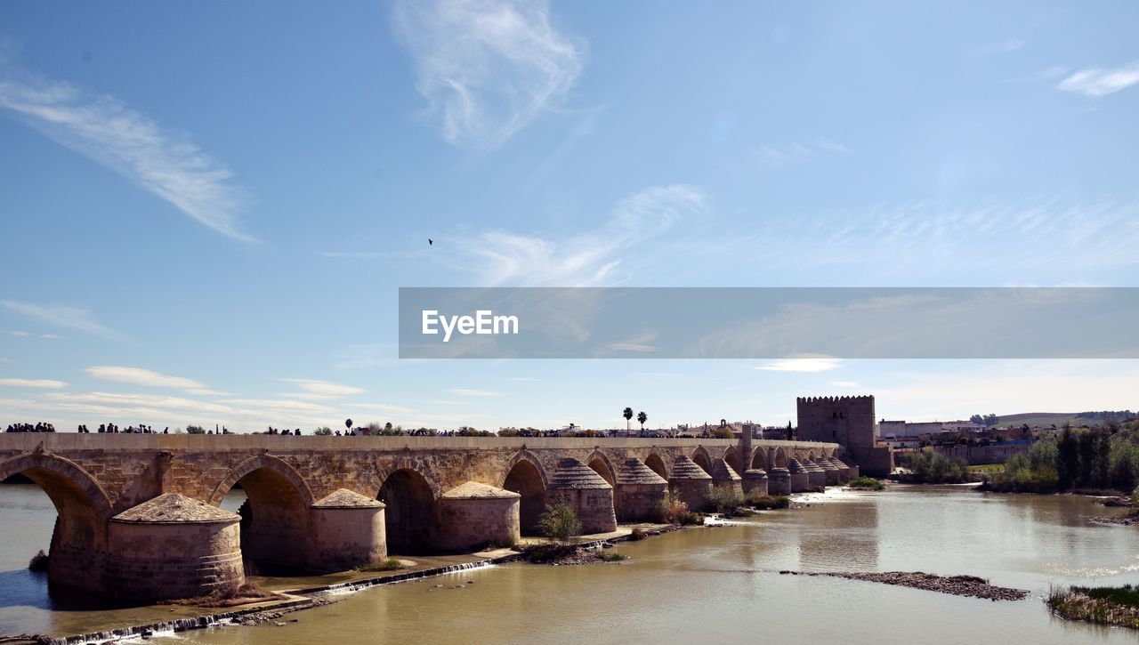Arch bridge over river against sky