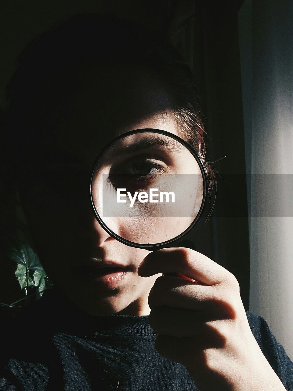 Close-up of woman looking through magnifying glass