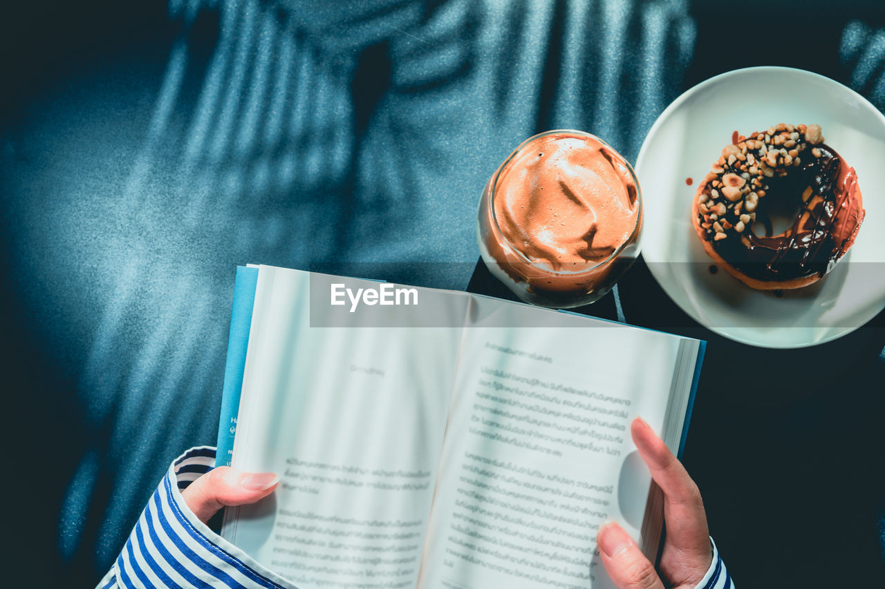 MAN HOLDING COFFEE CUP AND BOOK