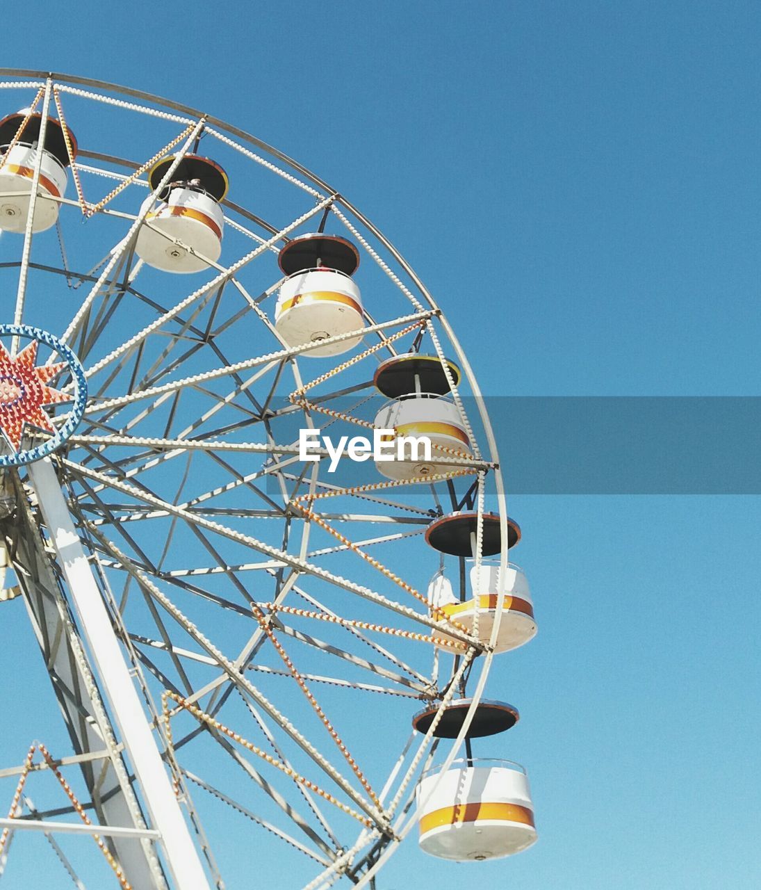 Low angle view of ferris wheel against clear blue sky