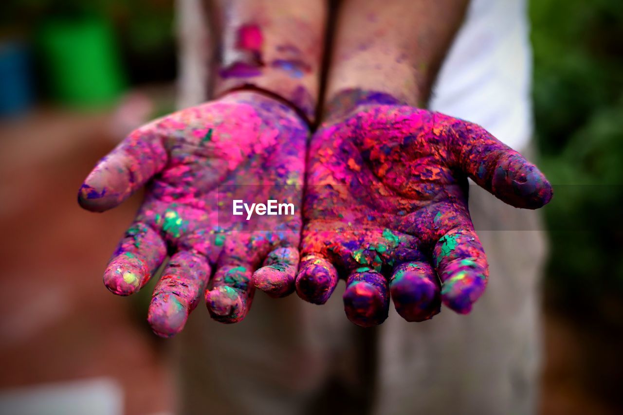 Cropped hands with multi colored powder paint