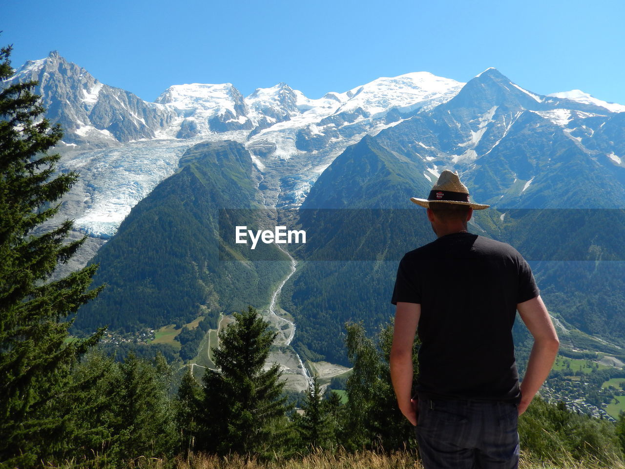 REAR VIEW OF MAN LOOKING AT MOUNTAINS