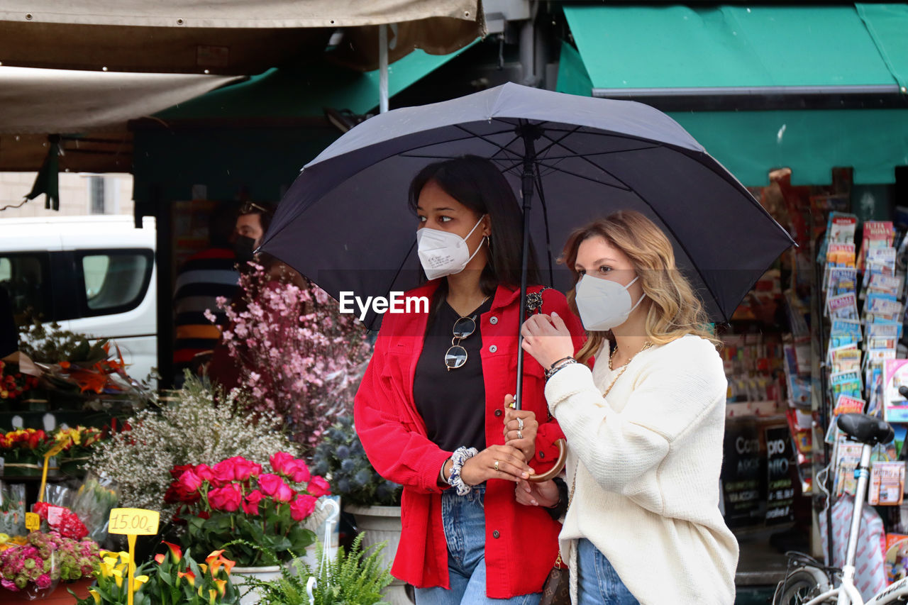 WOMAN HOLDING UMBRELLA STANDING IN MARKET