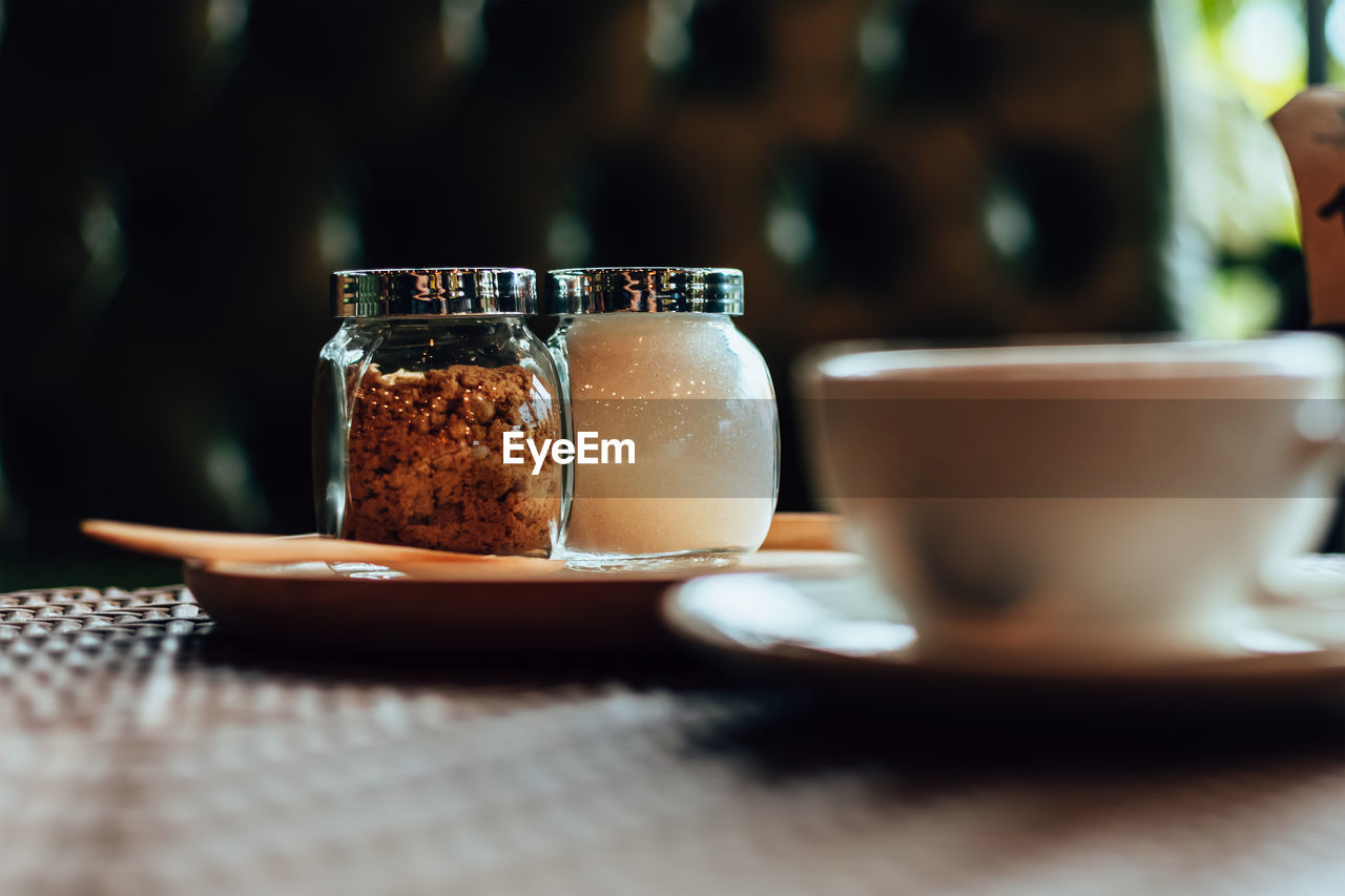 CLOSE-UP OF COFFEE CUP AND GLASS ON TABLE