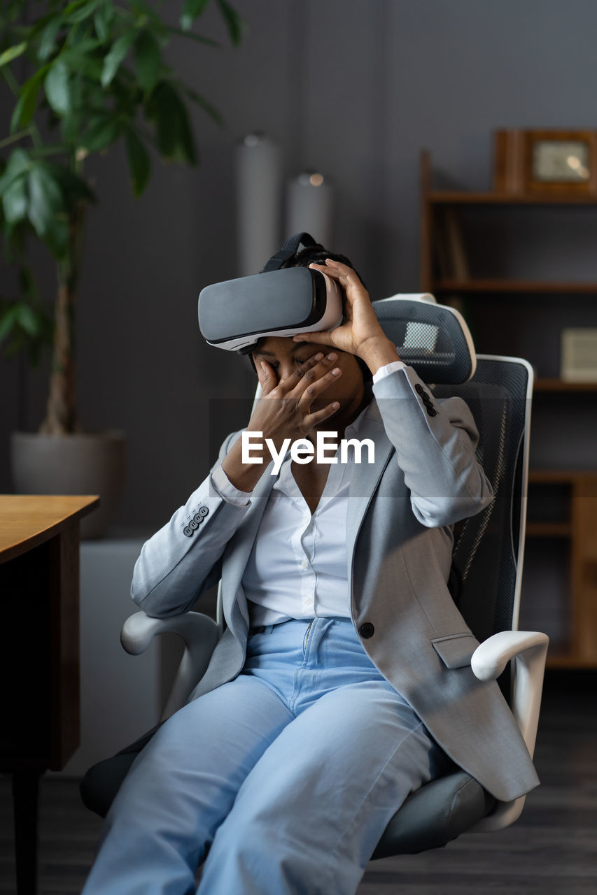 Frustrated african businesswoman unwell rub tired eyes from wearing vr goggles in office for work