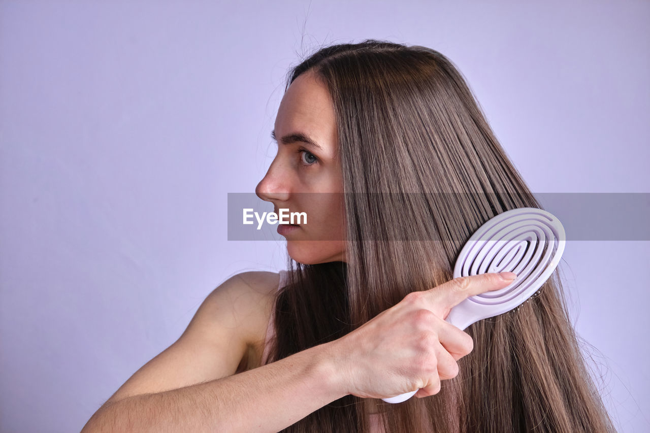 midsection of young woman holding headphones against white background