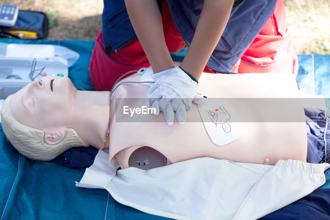 Midsection of person applying cpr to dummy outdoors