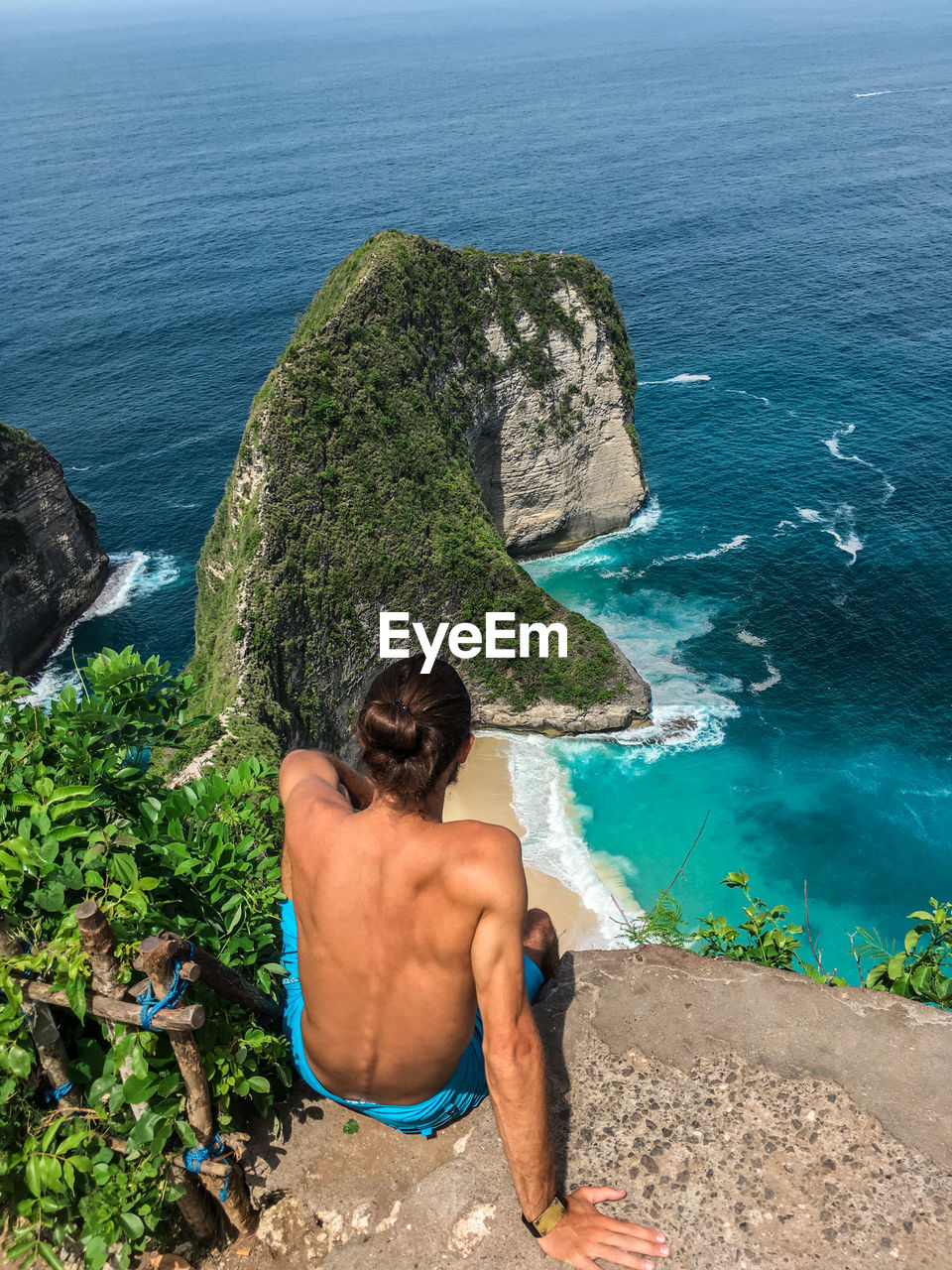 Rear view of shirtless man looking at sea