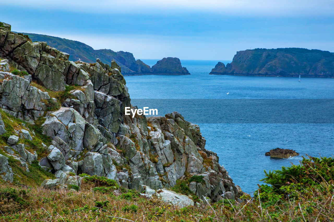 Scenic view of sea by mountains against sky