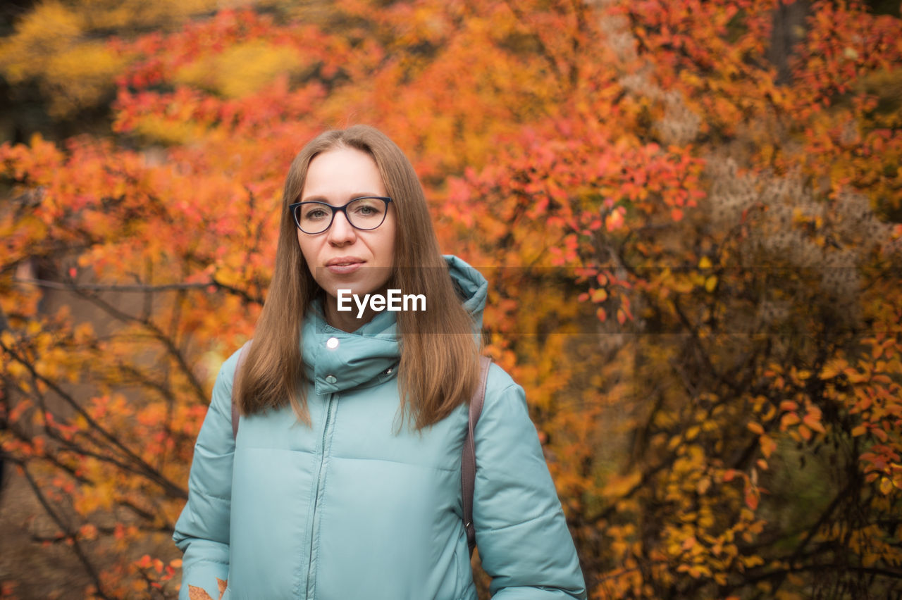 Portrait of beautiful woman standing against trees during autumn