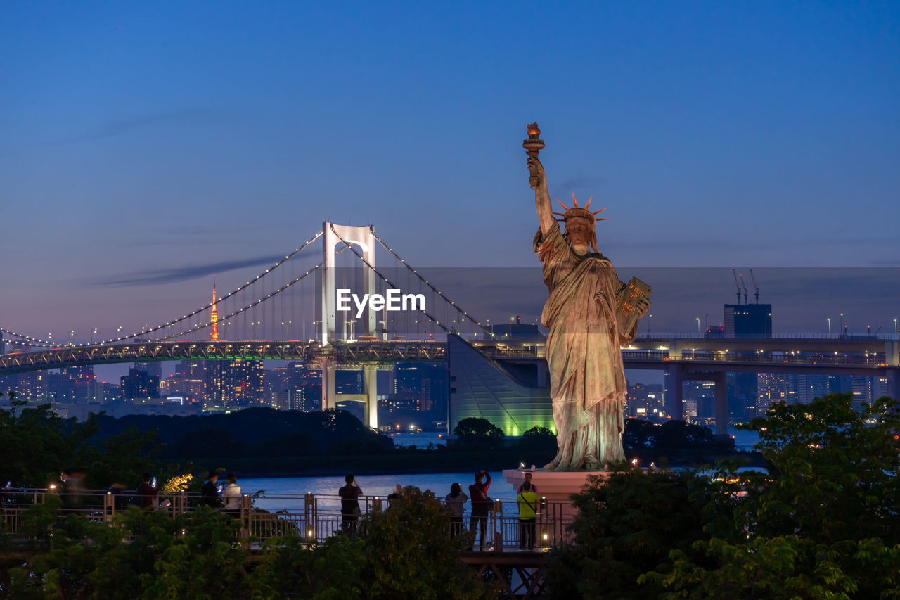 Statue of liberty against blue sky in city at night