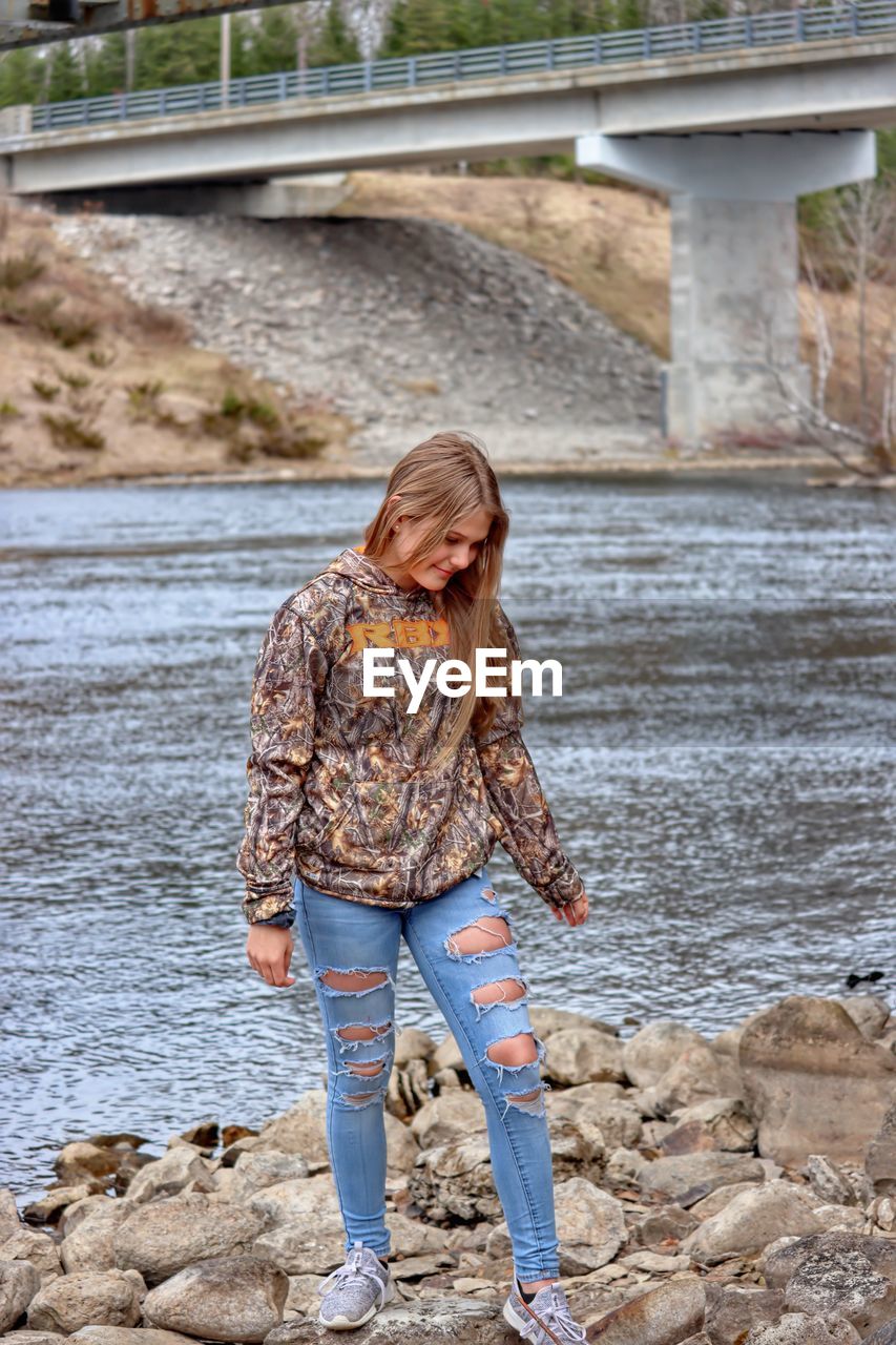 Young lady standing on rock by water