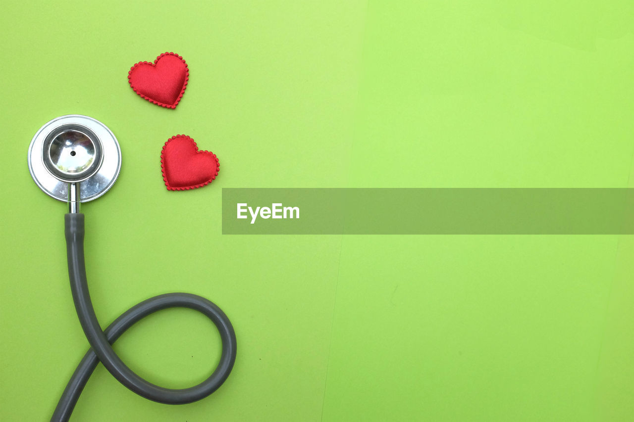 Flat lay red heart white stethoscope on green doctor table.health concept