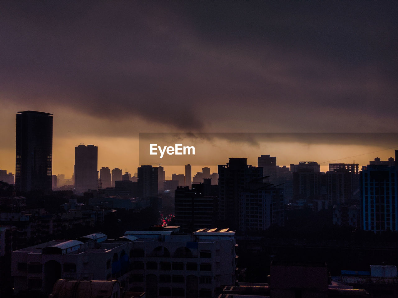 Silhouette buildings in city against sky during sunset