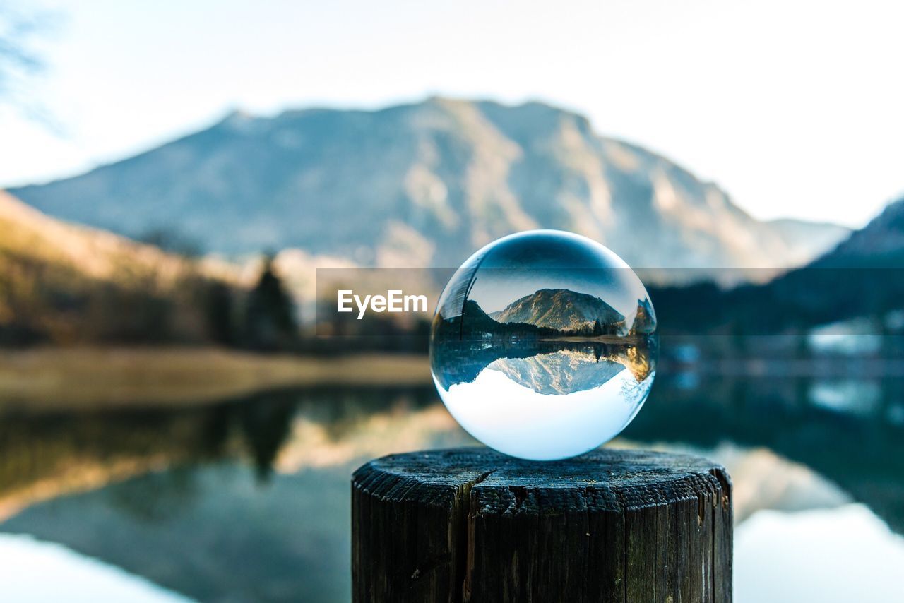 CLOSE-UP OF CRYSTAL BALL BY LAKE AGAINST MOUNTAINS