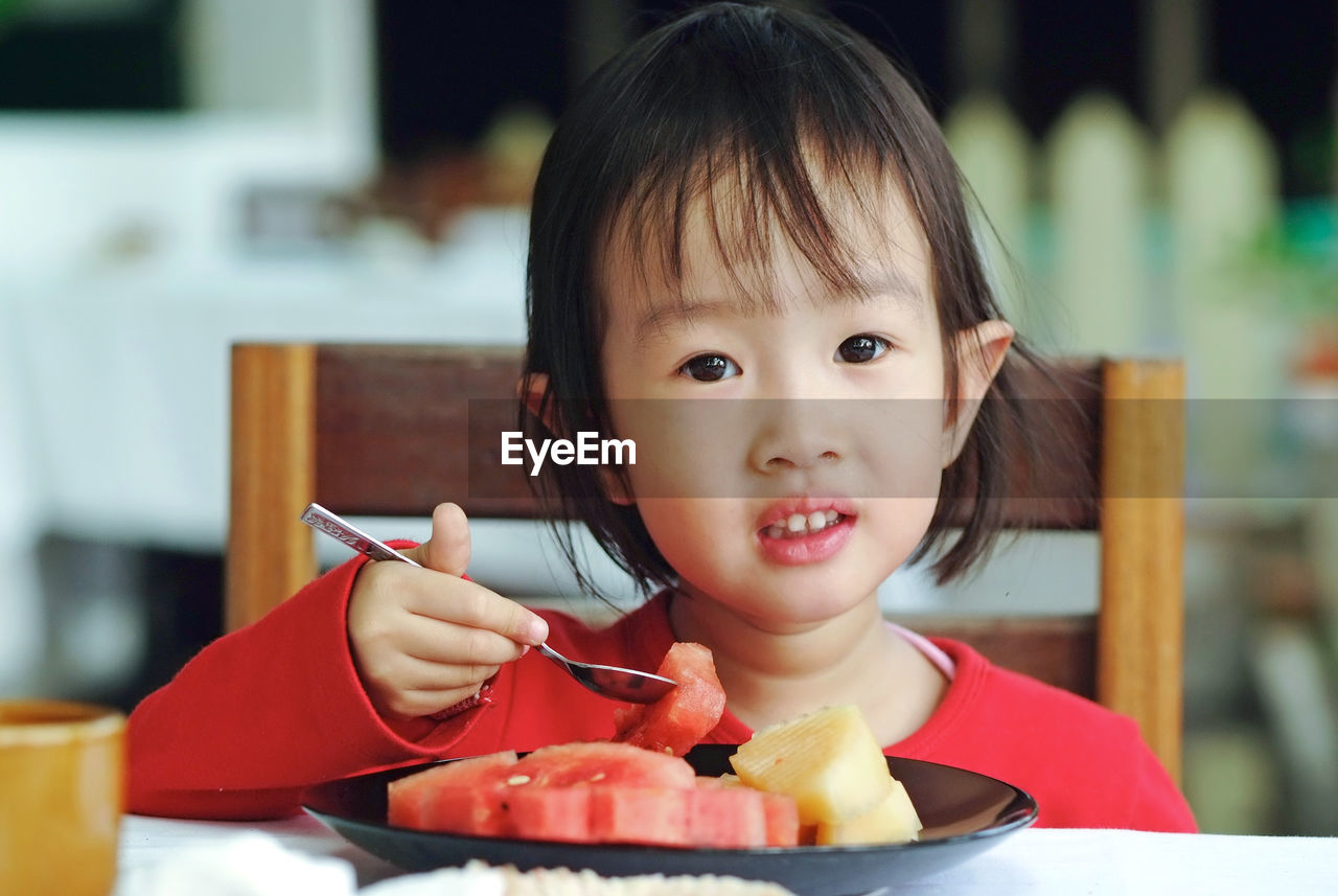 Close-up portrait of cute girl eating food at home