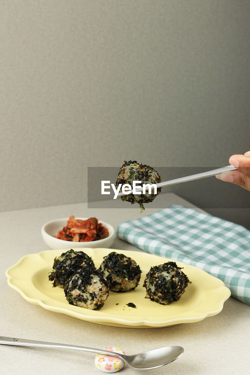 Female hand eat jumeokbap korean seaweed rice ball with kimchi. copy space for text