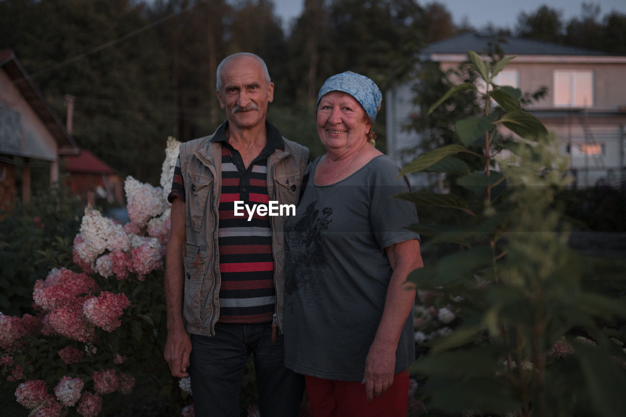 Portrait of smiling man and woman standing by plants