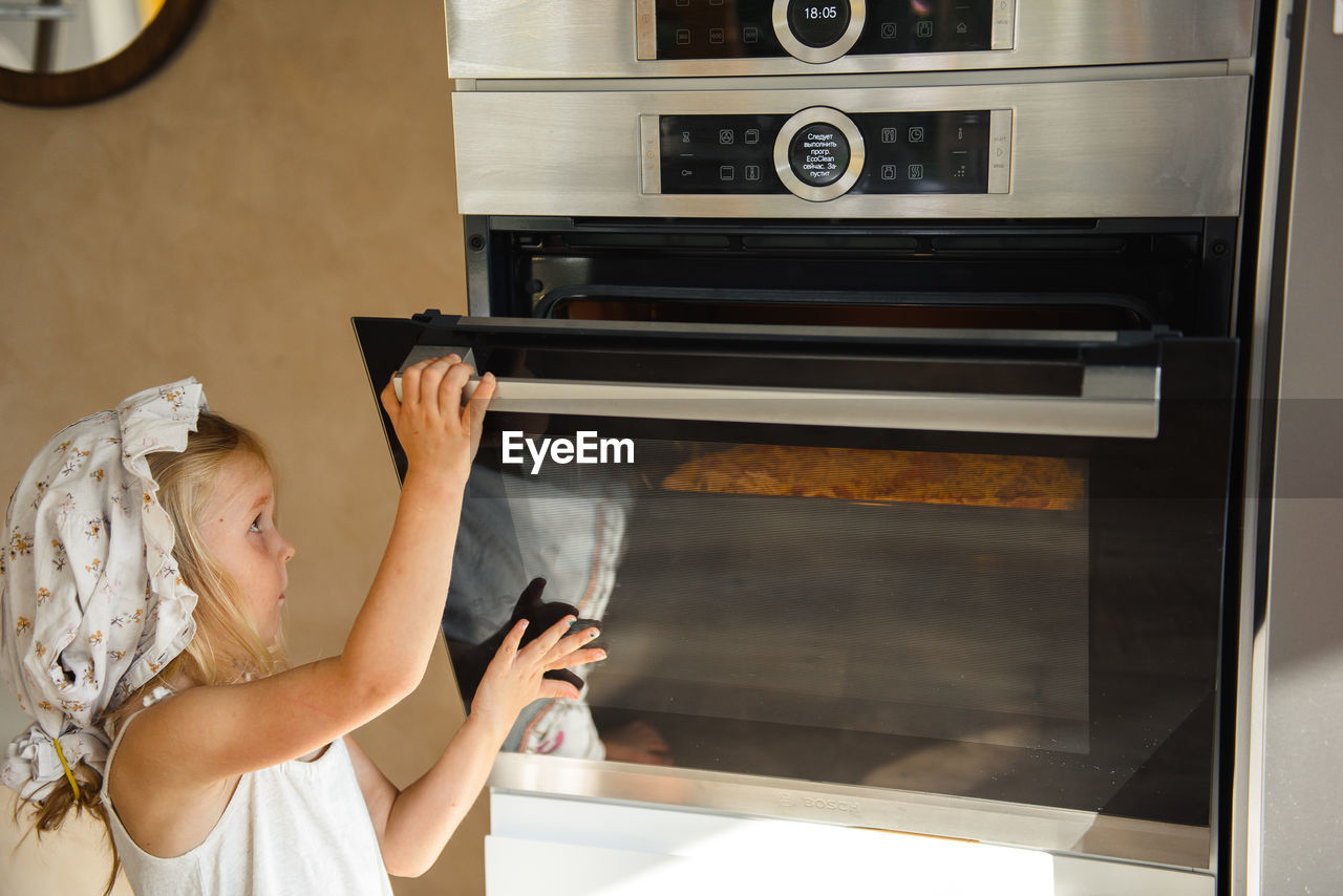 Little girl cooking pizza in the kitchen