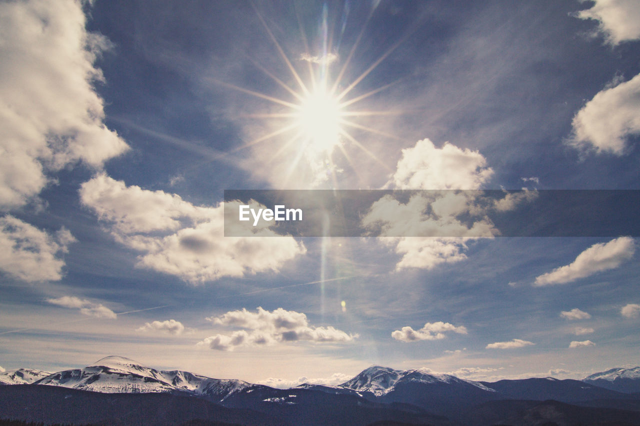 Panoramic sky with bright sun above mountain ranges landscape photo