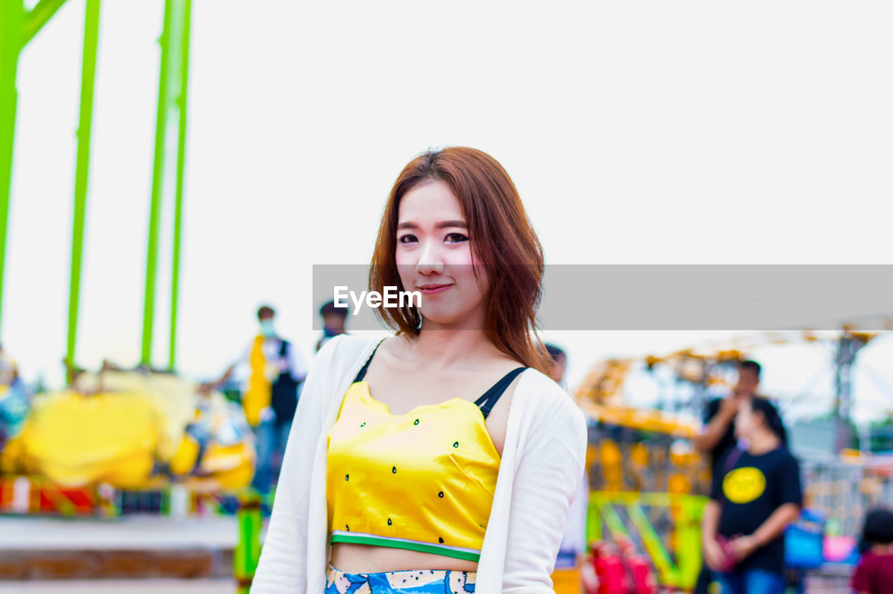 Portrait of young woman standing in amusement park