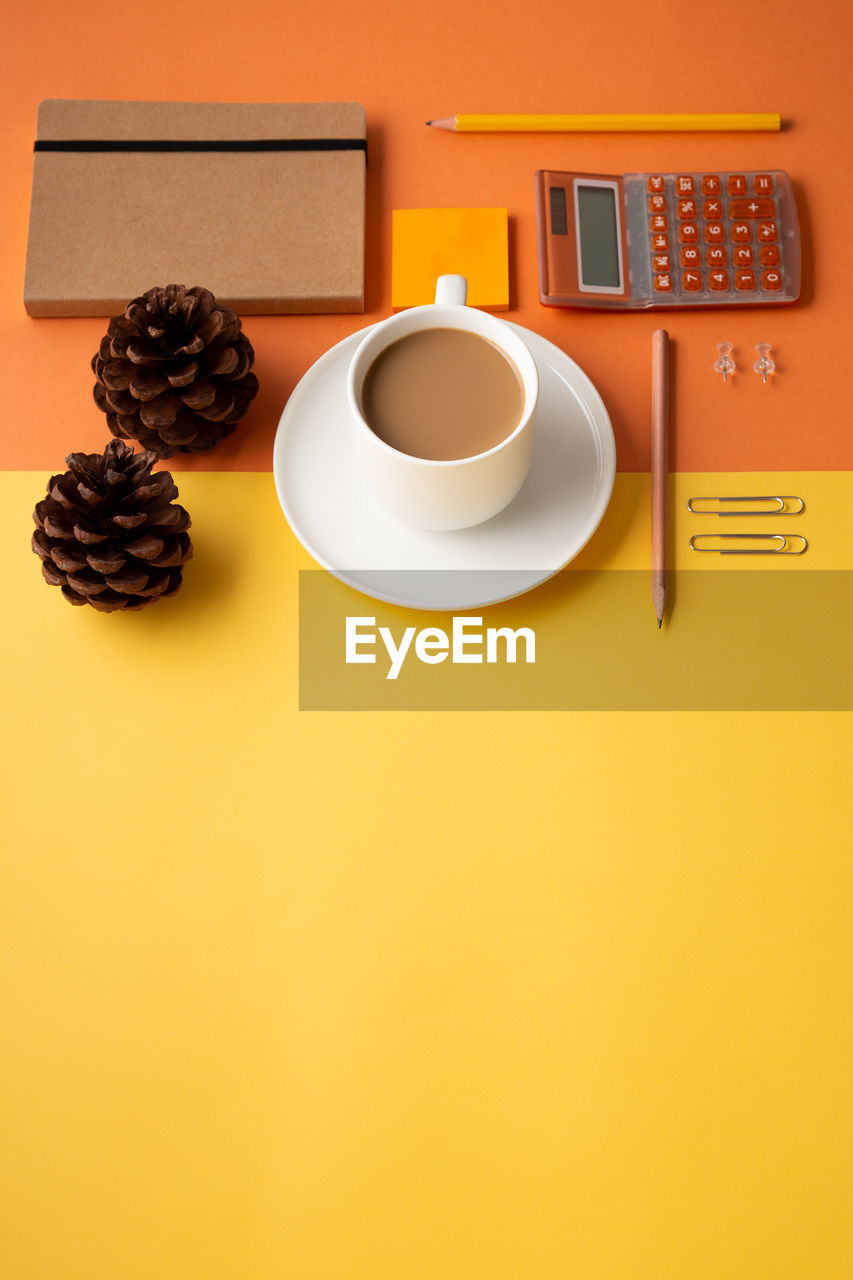 HIGH ANGLE VIEW OF COFFEE CUP AND ORANGE ON TABLE