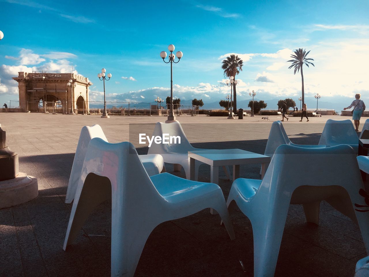 EMPTY CHAIRS AND TABLES AT RESTAURANT AGAINST SKY