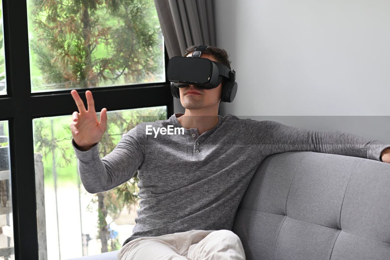 Man sitting on sofa using vr headset at home